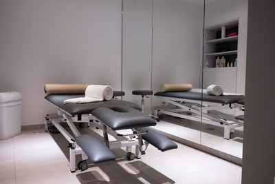Moderne Massagebank mit mehrfach verstellbaren Elementen in einem freundlichen hellen Raum und einer großen Spiegelwand
