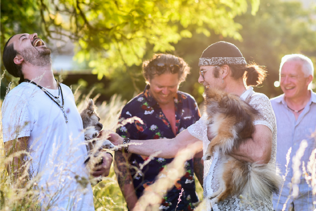 Marcel Adam mit kleinem Hund auf dem Arm umgeben von den übrigen Bandmitgliedern in der Natur